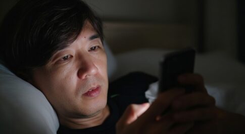 深夜にベッドの中でスマートフォンを見ている様子。
